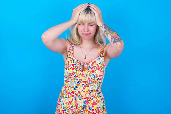 Caucasian Girl Wearing Floral Dress Isolated Blue Background Holding Head — Stock Photo, Image