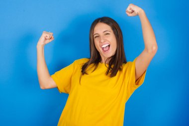 Evet, ben kazandım. Çekici, keyifli ve heyecanlı genç bir kadının portresi zafer ve zaferle yumruk kaldırıyor gülümsüyor ve mutluluktan sırıtarak başarı elde ediyor..