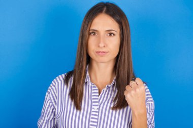 Güzel genç bir kadın yumruğunu gösterdi. İntikam almak isteyen ya da birini tehdit eden sinirli bir yüz ifadesi vardı. Sana patronun kim olduğunu göstereceğim.