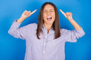 Çığlık atan ve parmakları saçları kapalı genç bir kadının fotoğrafı.