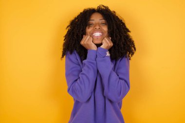 Sarı arka planda kulaklıkları olan Afro-Amerikan bir kadının portresi.