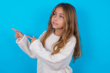 İyimser genç kız iki eliyle işaret ediyor ve boş alana bakıyor..