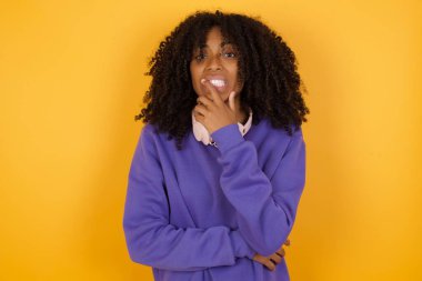 Sarı arka planda kulaklıkları olan Afro-Amerikan bir kadının portresi.