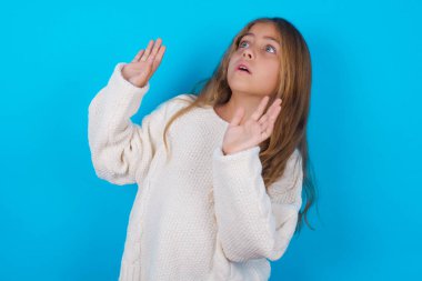 Güzel genç kız avuçlarını ileri uzatır ve tavandan korkuyla bakar kendini görünmez tehlikeden korumaya çalışır. Ağzını açar..