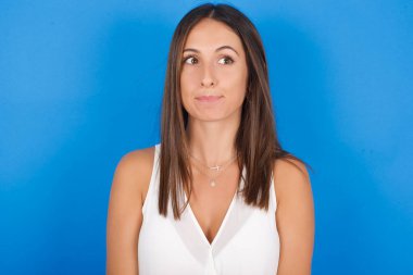 Şaşırmış genç bir kadın, kıvrımlı dudaklar ve endişeli bir bakış, önünde korkunç bir şey görüyor..