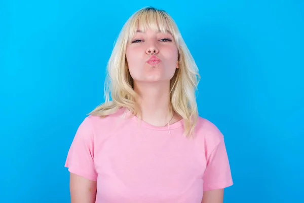 Biała Dziewczyna Ubrana Różowy Shirt Odizolowana Niebieskiego Tła Trzyma Usta — Zdjęcie stockowe