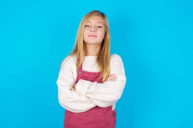 Kendine güveni tam, sakin, genç kız kollarını kavuşturmuş duruyor. Profesyonel titreşimlerin kendine güvenen pozlarda durduğunu gösterir.