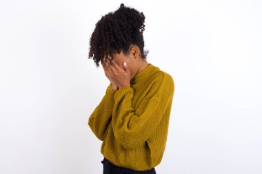 Üzgün genç bir kadın elleriyle yüzünü kapatıyor ve ağlıyor..