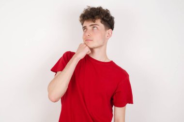 Düşünceli yakışıklı genç adamın portresi elini çenesinin altında tutuyor, bir şey hatırlamaya çalışıyor ya da ilgi çekici bir şey dinliyor. Gençlik kavramı.