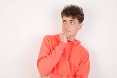 Yüz ifadeleri ve duygular. Düşünceli yakışıklı genç adam başının altında el ele tutuşuyor, şüpheli bakıyor..