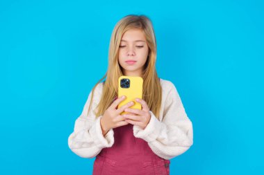 Gülümseyen genç kız cep telefonu kullanıyor, mesajlaşıyor, arkadaşlarıyla mesajlaşmaktan mutlu oluyor, akıllı telefona bakıyor. Modern teknolojiler ve iletişim.