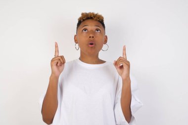 Güzel, zarif bir kadının portresi izole edilmiş arka planda şaşkın şaşkın bakıyor ve parmaklarıyla garip bir şey gösteriyor..