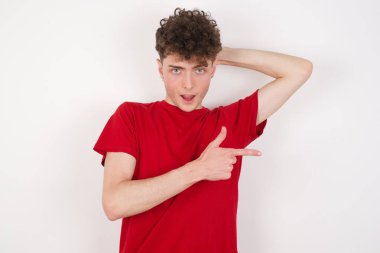 Yakışıklı genç bir adamın olumlu düşünmesi, şaşkınlık verici bir ifadeye işaret ediyor. Bir elin başının üstünde, diğer elinle işaret et..