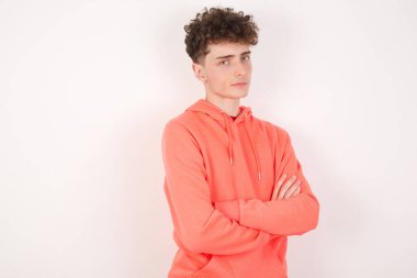 Kendine güvenen genç adamın belinde geniş bir gülümseme, kollarını kavuşturur, iş arkadaşlarıyla tanıştığına memnun olur..