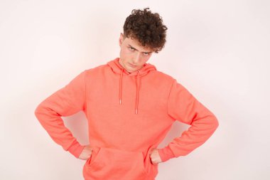 Beyaz arka plandaki komik, hayal kırıklığına uğramış yakışıklı genç adam el ele tutuşuyor ve garip durumlara bakıyor..