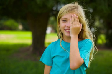 Parkta mavi tişört giyen beyaz güzel bir kızın portresi.