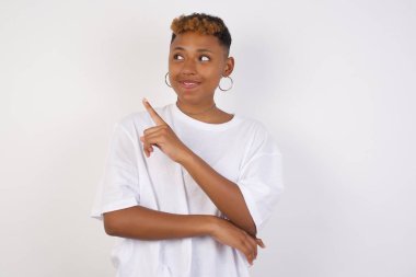 Kamerada poz veren güzel siyahi kadın. İnce bakışlı ve el kol hareketi yapan. Bayan tasarımcı, işaret parmağıyla harika bir ürün sunuyor. Hareket kavramı.