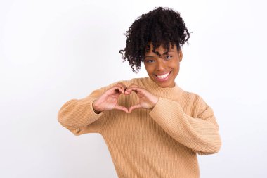 Elleriyle kalp sembolü ve şekli gösteren, aşık bir genç kadın. Romantik konsept.