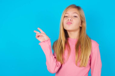 Güzel kız barış jesti yapıyor. Dudakları kapalı, V işaretini koruyor. Vücut dili kavramı