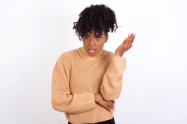 Studio shot of frustrated young woman gesturing with raised palm, frowning, being displeased and confused with dumb question.