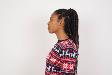 Beyaz duvara karşı Noel süveteri giyen Afro-Amerikalı kadının arka görüntüsü. Stüdyo Çekimi.