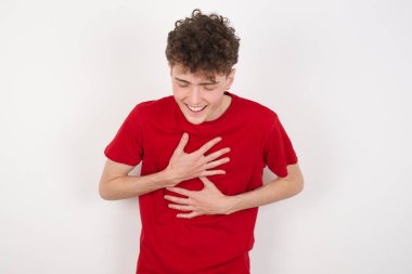 Beyaz arka plandaki yakışıklı genç adam ellerini çapraz yapar, güzel şakalara yüksek sesle güler, günlük kıyafetler giyer..