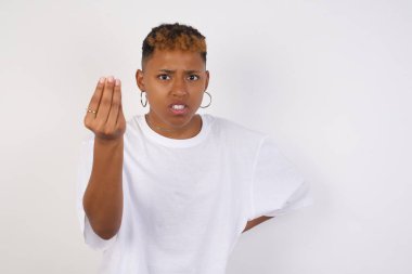What the hell are you talking about. Shot of frustrated young African American woman wearing white t-shirt gesturing with raised hand doing Italian gesture, frowning, being displeased and confused with dumb question.