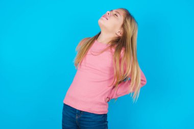 Güzel bir kızın mavi arka planda sırt ağrısı var.