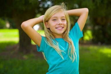 Parkta mavi tişört giyen beyaz güzel bir kızın portresi.