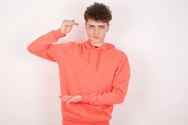 Beyaz arka plandaki yakışıklı genç adam. Elleri büyük ve büyük bir işaret, ölçü sembolü gösteriyor..