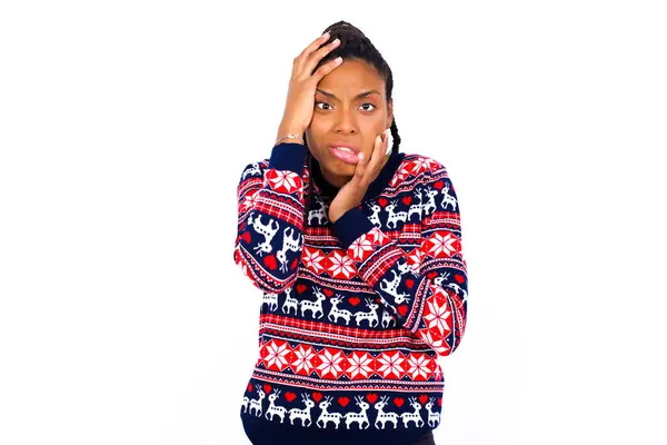 身穿圣诞毛衣 头戴白墙 满脸皱纹 哭哭啼啼 站在那里抱怨工作问题的年轻而忧郁的非洲裔美国女人 — 图库照片