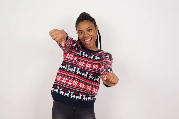 彼女の頭の上に手を握りながら広く笑顔でクリスマスセーターを着た魅力的なアフリカ系アメリカ人女性の肖像画 自信とリラックスのコンセプト — ストック写真