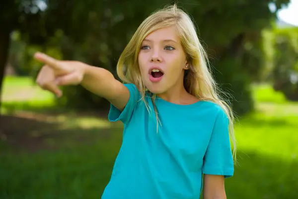 公園の屋外に立っている青いTシャツを身に着けている美しい白人少女の肖像画 — ストック写真