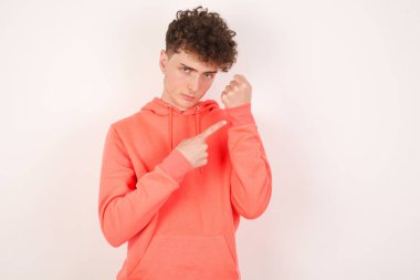 Beyaz arka planda yakışıklı bir genç adam. Aceleyle saati, sabırsızlığı, gecikme yüzünden kızgın ve sinirli olduğunu gösteriyor.