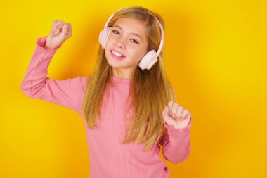 Kaygısız, güzel, kalın sakallı, dişlek gülümsemeli, kollarını kaldıran, gamsız hareketlerle müziğin ritmiyle müzik dinleyen kulaklıklı bir kız.