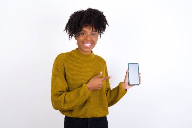 Gülümseyen genç bir kadın boş telefon ekranını gösteriyor ve işaret ediyor. Reklam ve iletişim konsepti.