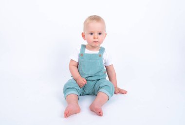 Stüdyo portresi. Beyaz stüdyo arka planında yeşil giyinmiş şirin bir çocuk resmi.