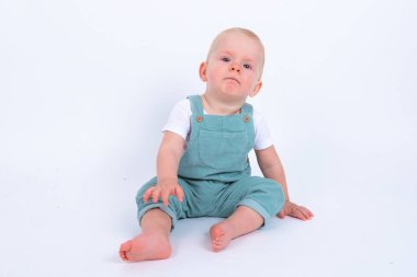 Stüdyo portresi. Beyaz stüdyo arka planında yeşil giyinmiş şirin bir çocuk resmi.