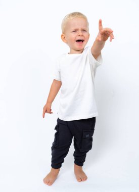 Beyaz tişört ve siyah pantolon giyen güzel sarışın çocuk portresi. Beyaz stüdyo arka planında poz veriyor.