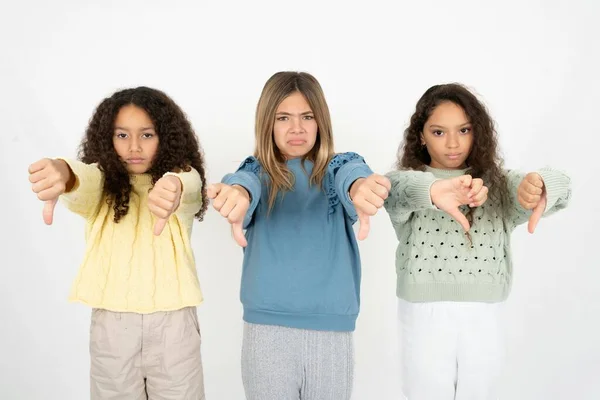 3人のティーンエイジャーの女の子は 両手で親指を見せて動揺しています 嫌いなコンセプト — ストック写真
