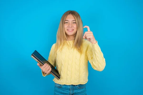 beautiful kid girl wearing yellow sweater over blue background pointing up with fingers number nine in Chinese sign language Jiu