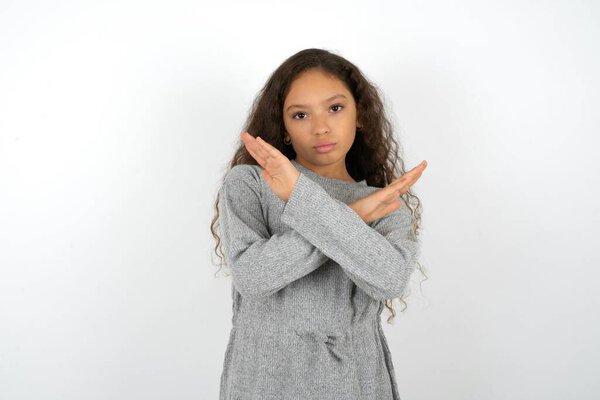 Teenager girl wearing grey dress against white background Rejection expression crossing arms doing negative sign, angry face