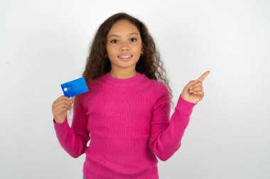 Pembe kazak giyen gülümseyen genç kız bankamatik kartını göstererek boş bir yeri işaret ediyor.