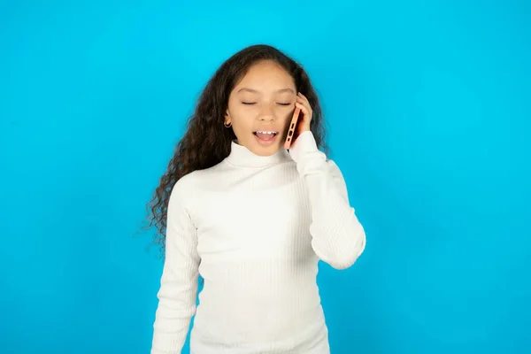 ホワイトセーターを着ている幸せなティーンエイジャー少女は 電話会話中に友人からの面白い話を積極的に聞きます — ストック写真