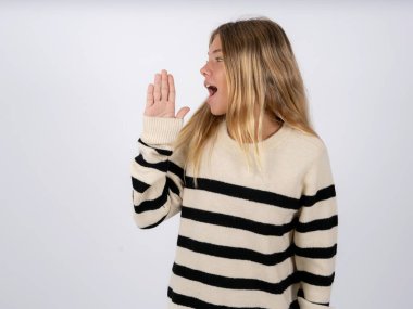 Yarım yamalak, beyaz arka plan üzerinde çizgili örgü süveter giyen, ağzı yakınında el ele tutuşan hayretler içinde beyaz bir genç kızın portresi. 