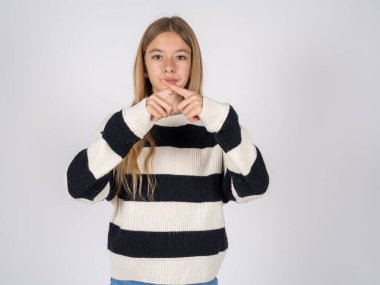 Beyaz stüdyo geçmişinde çizgili süveter giyen güzel bir genç kız reddedilmiş kızgın bir ifadeyle negatif işaret veriyor..
