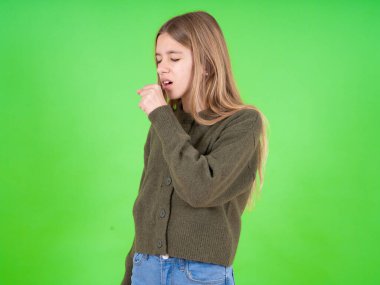 Yeşil kazak giyen güzel beyaz kız kendini kötü hissediyor ve soğuk algınlığı veya bronşitin belirtisi olarak öksürüyor. Sağlık hizmetleri kavramı.