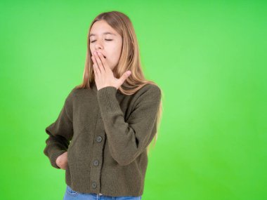 Güzel beyaz kız, yeşil kazak giyiyor. Bütün gün çalıştıktan sonra yoruluyor ve esniyor..