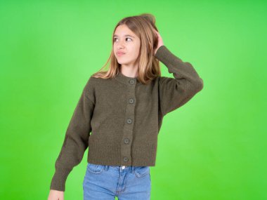 Yeşil kazak giyen güzel beyaz kız soru sormayı merak ediyor. Şüpheyle kararsız, kafa kafaya düşünerek. Düşünceli kavram.