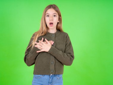 Korkmuş, beyaz, yeşil süveter giyen, korkmuş bir ifade takınan, elleri göğsünde olan, garip bir şey fark eden güzel bir beyaz kız..